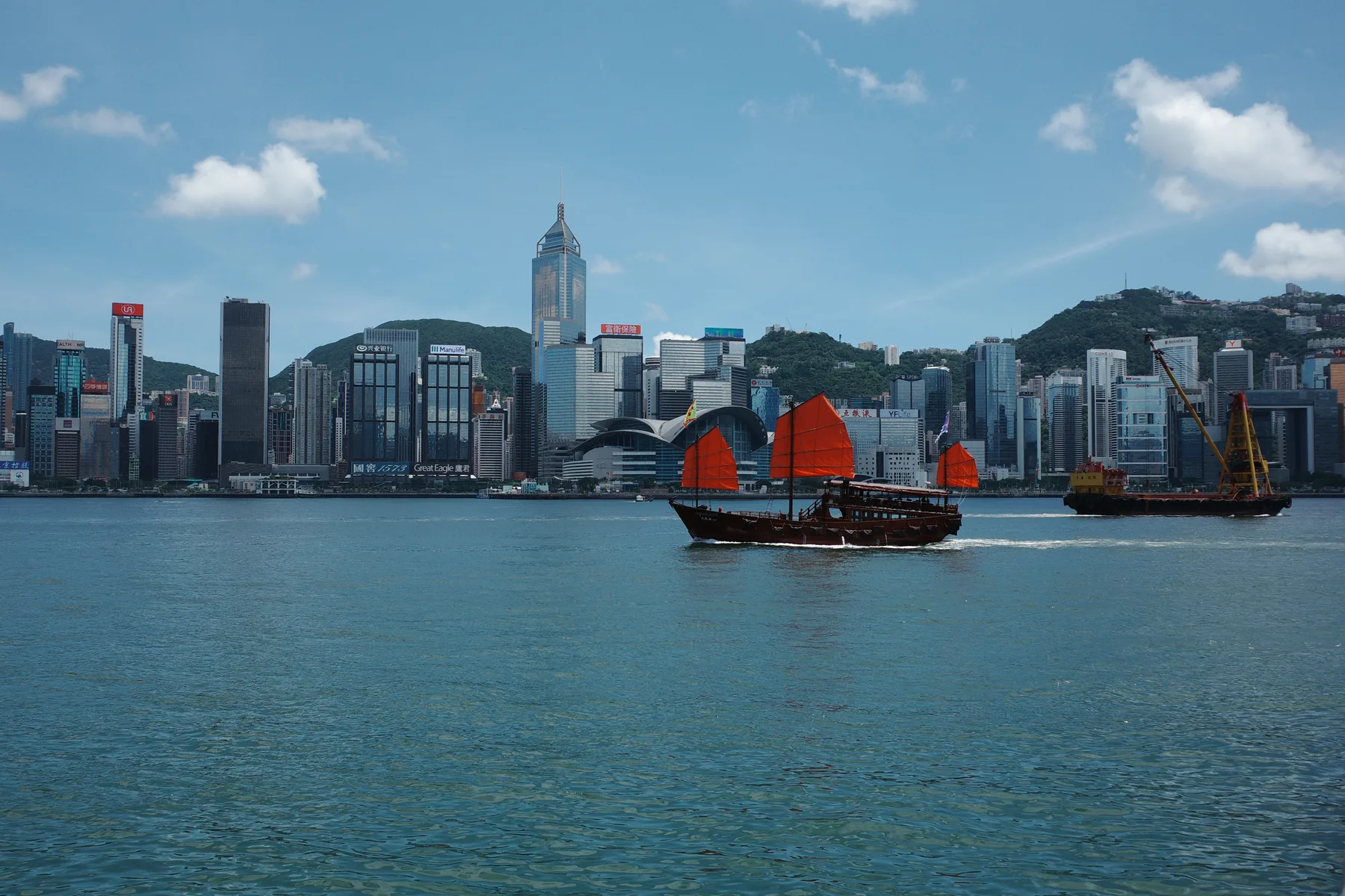 A red-sailed boat crossing Hong Kong harbour