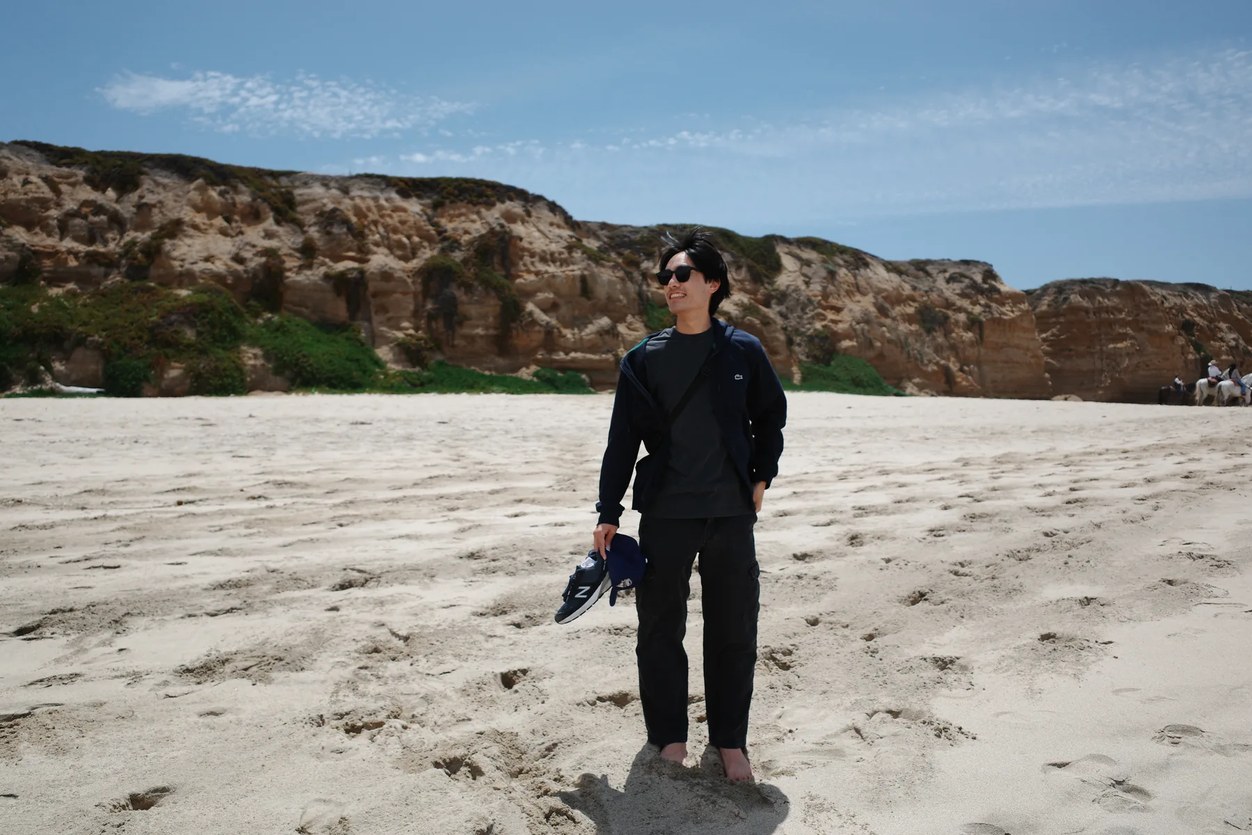 David Wong standing on a bright beach beneath a wide blue sky